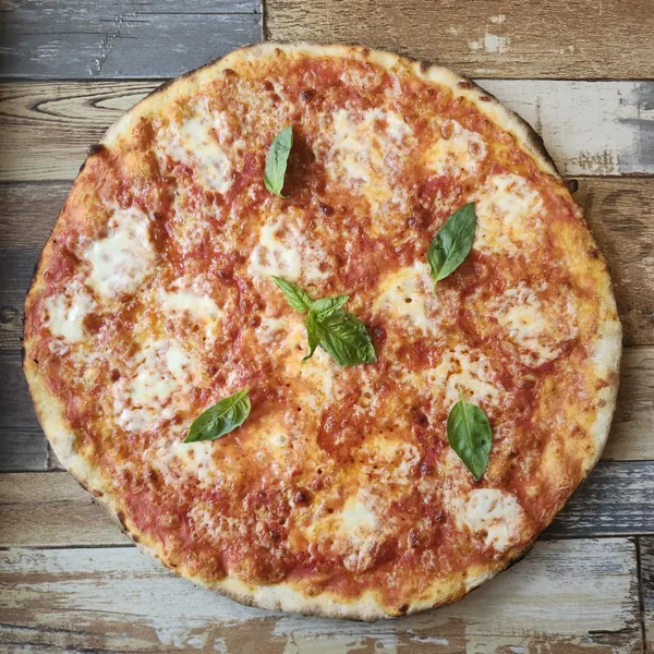 A thin red pizza with mozzarella and a few basil leaves
